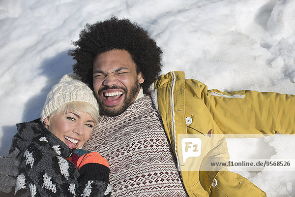 Portrait of happy couple laying in snow