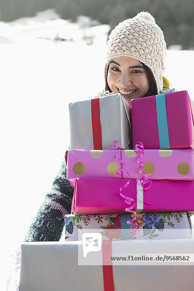 Portrait of smiling woman carrying stack of gifts