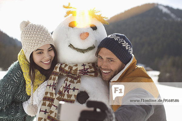 Couple taking selfie with snowman