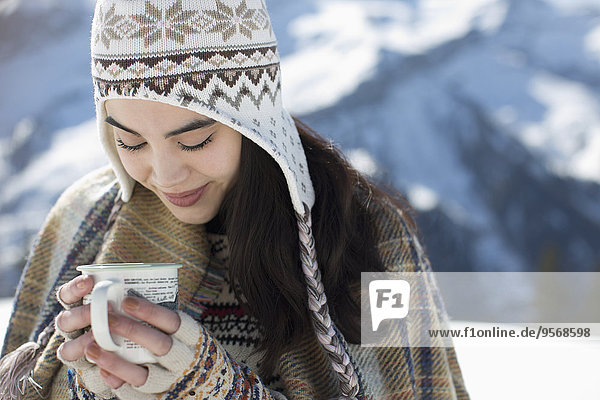 Smiling woman in knit hat drinking hot cocoa outdoors