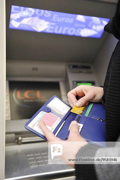 Junge Frau zieht Geld von einem Geldautomaten ab