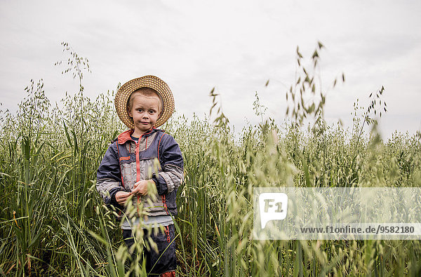 Caucasian boy standing in tall grass in rural field
