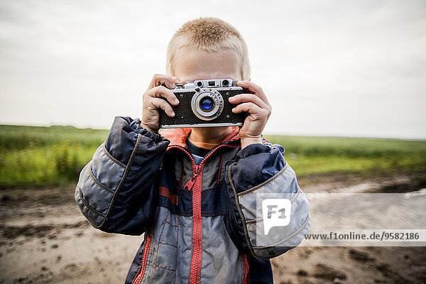 Caucasian boy taking photograph in rural field