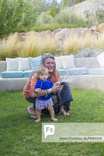 Caucasian grandmother hugging baby grandson in backyard