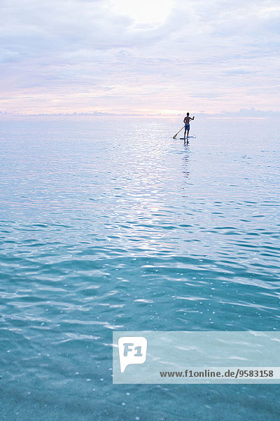 Caucasian man standing on paddleboard in ocean