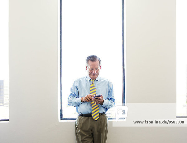Caucasian businessman using cell phone in office