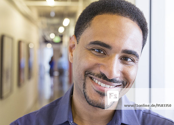 Black businessman smiling in office hallway