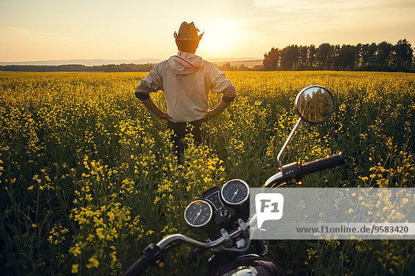 nahe stehend Mann Blume Feld Motorrad