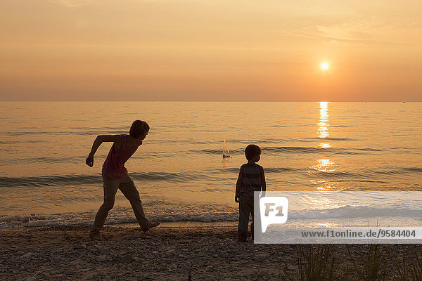 Caucasian brothers playing on beach at sunset