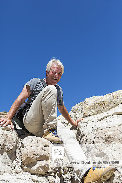 Older Caucasian man climbing rock formations