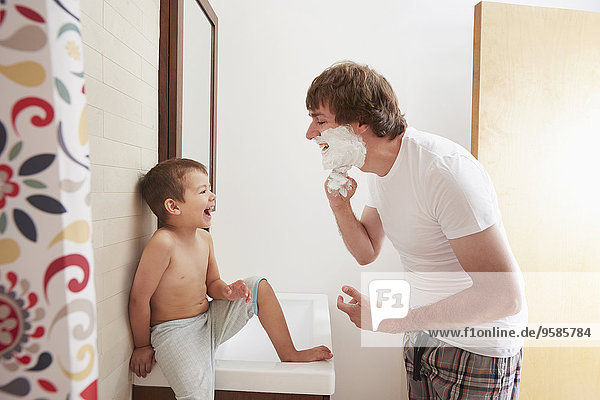 Father teaching son to shave in bathroom
