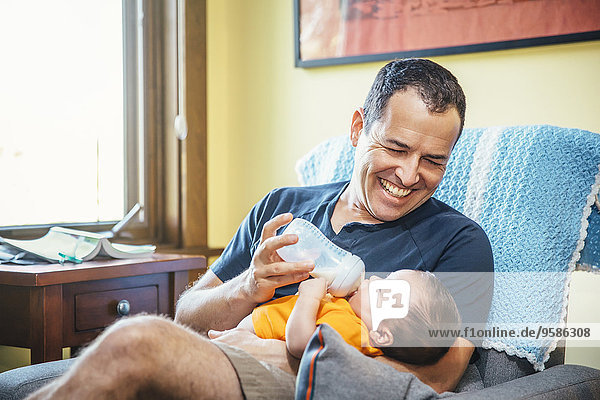 Caucasian father feeding baby boy in living room