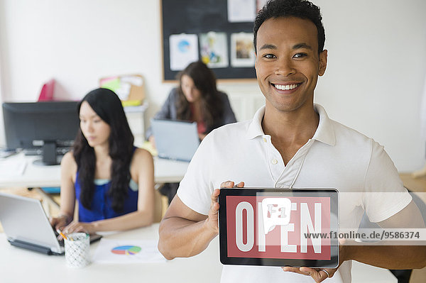 Businessman holding open sign on digital tablet in office