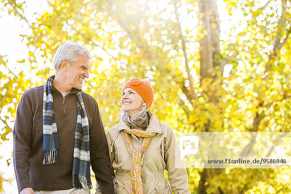Older Caucasian couple walking near autumn trees