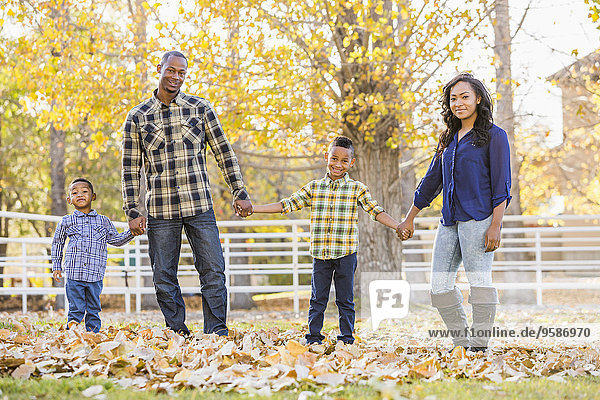 Family holding hands in autumn leaves