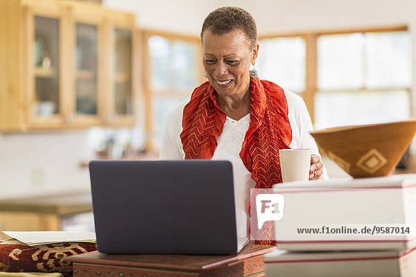 Older mixed race woman using laptop in home office