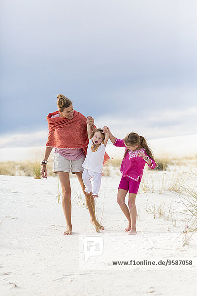 Caucasian mother and children walking on sand dune