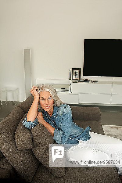 Portrait of mature woman sitting on the couch in her living room