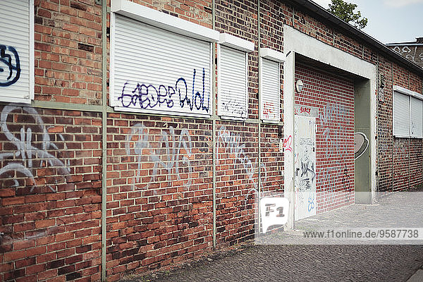 Deutschland  Sachsen  Leipzig  Graffiti an der Fassade und geschlossene Rollläden eines alten Industriegebäudes