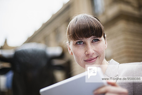 Germany  Hesse  Frankfurt  portrait of smiling businesswoman with digital tablet in front of stock market