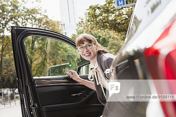 Porträt einer lächelnden Geschäftsfrau beim Aussteigen aus dem Auto