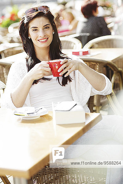 Fröhliche junge Frau entspannt in einem Straßencafé