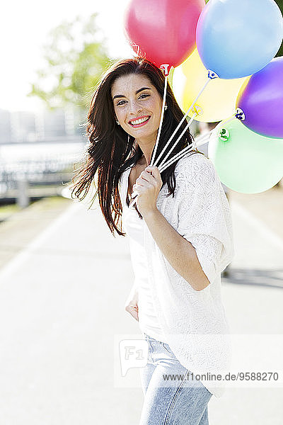 Portrait einer glücklichen jungen Frau mit einem Haufen Luftballons