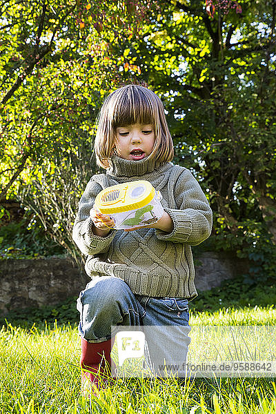 Little girl with insect can in the garden