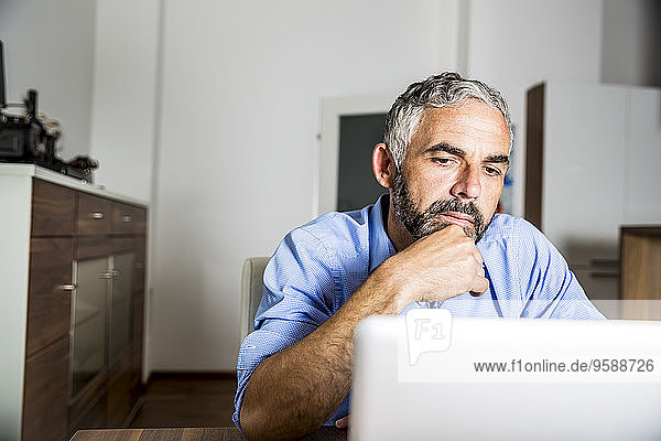 Portrait of businessman working with laptop at home office