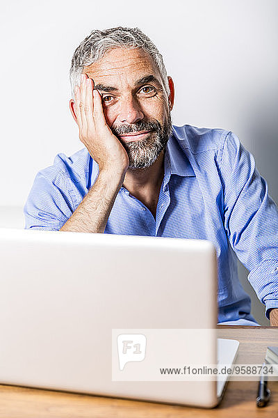 Porträt eines lächelnden Geschäftsmannes mit Laptop in seinem Home Office