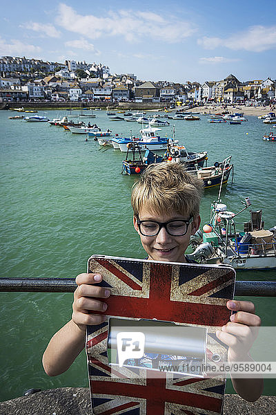 UK  Cornwall  smiling boy taking a selfie at St Ives with his digital tablet
