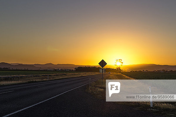 Australien  Queensland  Straße mit Bergkette bei Sonnenaufgang