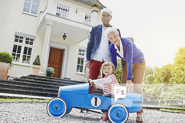 Deutschland  Hessen  Frankfurt  Seniorenpaar mit Enkelin sitzend Tretauto