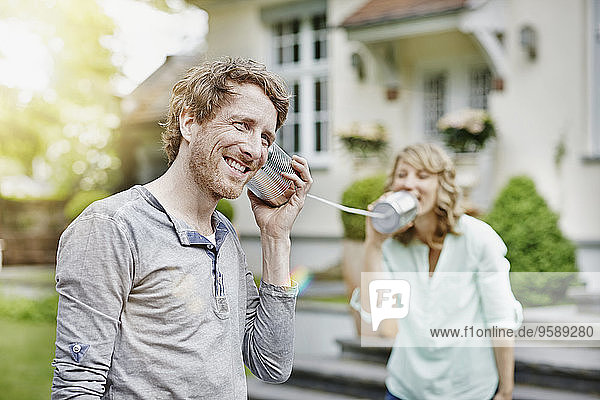 Deutschland  Hessen  Frankfurt  Paar im Garten spielen mit Blechdose Telefon
