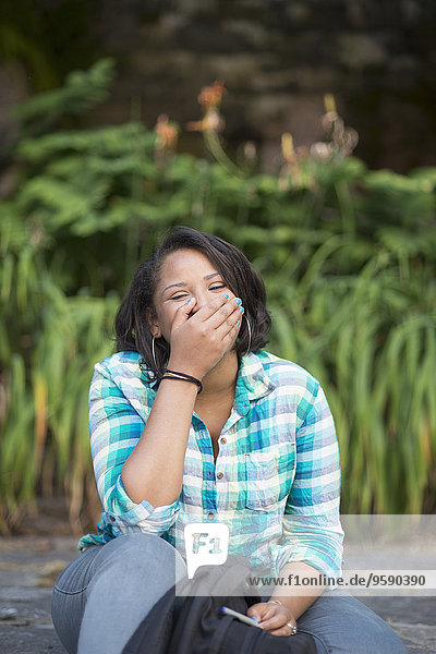 Young woman laughing with hand covering mouth