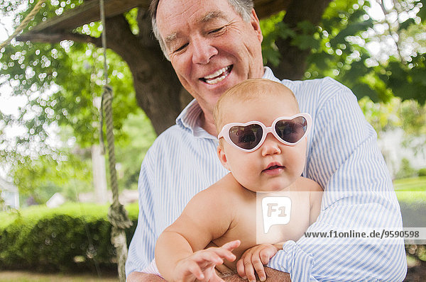 Portrait von Großvater und Enkelin in herzförmiger Sonnenbrille