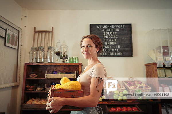 Porträt einer Verkäuferin mit Obst- und Gemüsekiste im Landhaus