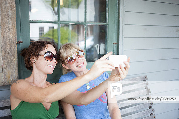 Zwei erwachsene Frauen nehmen Smartphone Selfie auf der Veranda