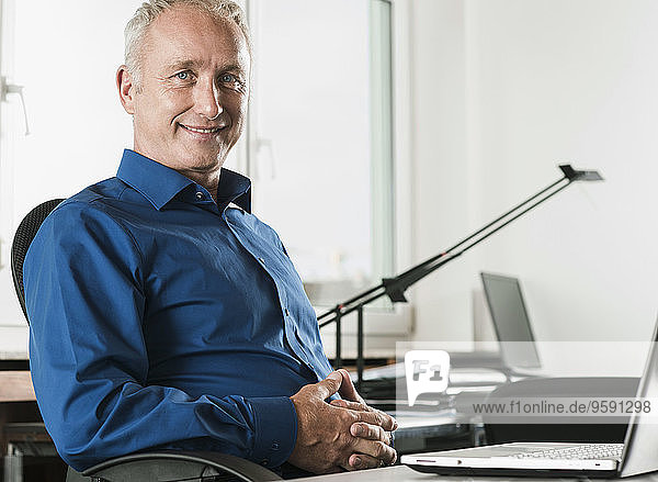 Portrait of smiling businessman at desk