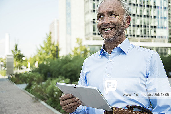 Lächelnder Geschäftsmann mit digitalem Tablett im Freien