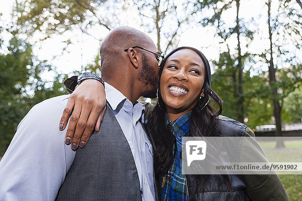 Man kissing woman's cheek in park