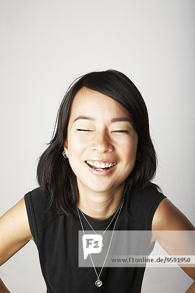 Studio portrait of mid adult woman laughing with eyes closed