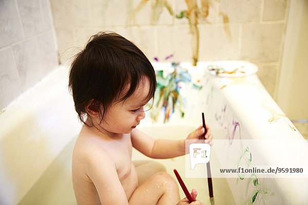 Male toddler painting in bath