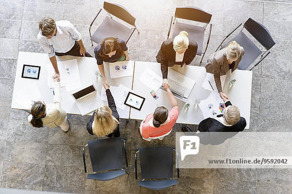 Overhead view of business team meeting clients at desk in office