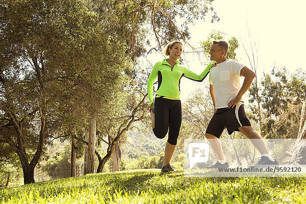 Mature running couple warming up in park