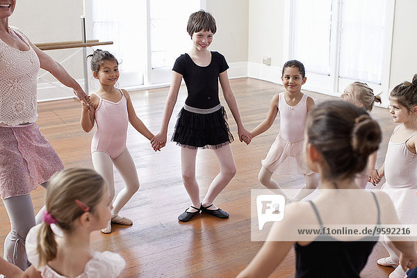 Kinder und Lehrer im Kreis üben Ballett in der Ballettschule