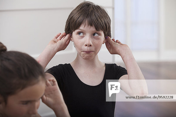 Girl with holding ears pulling a face in ballet school