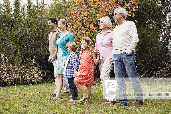 Großfamilie geht Hand in Hand im Garten spazieren