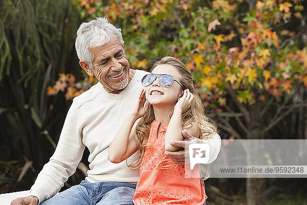 Grandfather and happy granddaughter with sunglasses outdoors