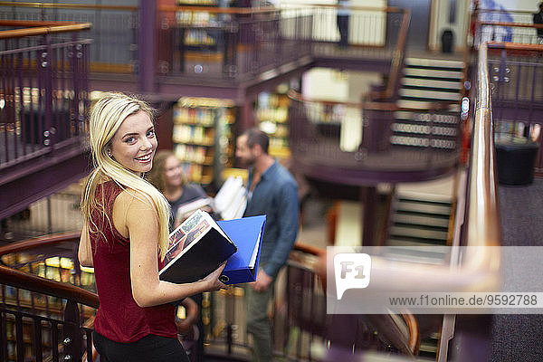 Porträt einer lächelnden Studentin in einer Bibliothek